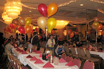 A banquet hall set with long tables and balloons